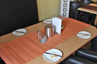 Dining table with four place settings including chopsticks and napkins on white plates, a metal container, salt and pepper shakers at Hotel G&auml;stehaus Centro Albert GmbH