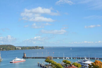 View of a harbor with boats, a pier with flags, and a distant shoreline from Hotel G&auml;stehaus Centro Albert GmbH