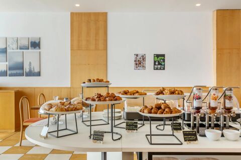 Pastry buffet with croissants, muffins, and spreads displayed on a white table at B&B Hotel Cuneo Cristal dining area