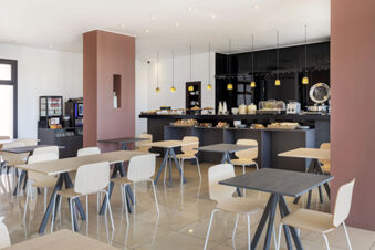 Dining area with wooden tables and chairs and a breakfast buffet counter in B&B Hotel Sassuolo