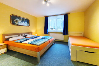 Room at Pension K&ouml;nigshof featuring a double bed, single bed, blue carpet, yellow walls, and a window with blue curtains