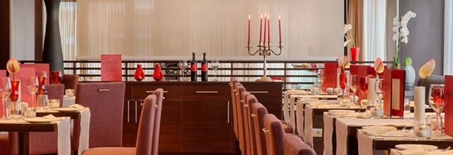 Dining area with purple chairs, dark wood tables, red glassware, candles, flowers, and menus at NH Collection Roma Giustiniano
