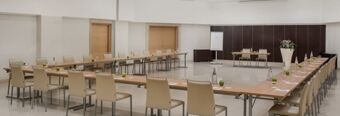 Large conference room at NH Collection Roma Giustiniano with U-shaped table setup and beige chairs around the tables