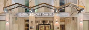 Entrance of NH Collection Roma Giustiniano hotel with illuminated modern metal canopy and revolving glass door at night