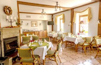 Jasna i przytulna restauracja z kominkiem i nakrytymi stołami w hotelu Gasthof Cosch&uuml;tz jest idealnym miejscem na posiłek i odpoczynek.
