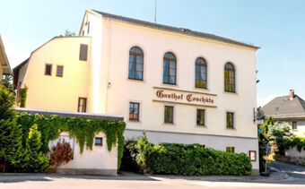 Fasada hotelu Gasthof Cosch&uuml;tz to jasny, dwupiętrowy budynek z dużymi oknami i zielonymi ścianami zewnętrznymi przy słonecznej ulicy.