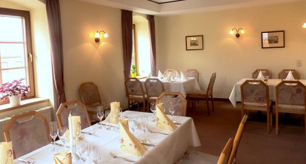 Jasna i przytulna restauracja z zadaszonymi stolikami i oknami w hotelu Gasthof Cosch&uuml;tz na relaksujący posiłek.
