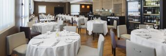 Dining area with round tables covered in white cloth and neatly set silverware at NH Milano Fiera