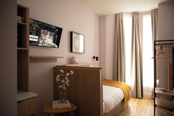 Modern hotel room interior at Bob W London Holland Park with bed, wall-mounted TV, window, and wooden furniture