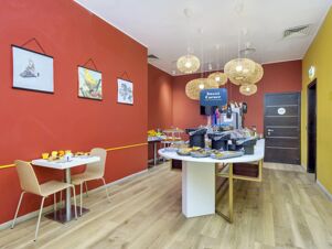 Interior of a dining area at B&B Hotel Milano-Monza with hanging lights, a buffet table, and paintings on red walls