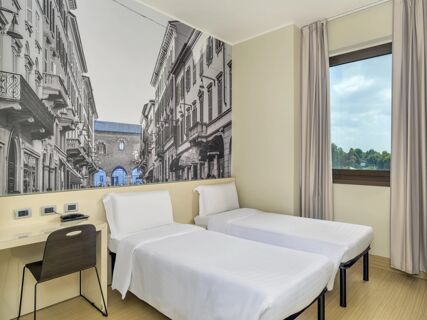 Two single beds with white linens and a wall mural of buildings in a B&B Hotel Milano-Monza guest room