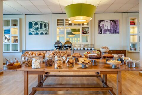 Breakfast buffet with pastries, cookies, fruits, jams, and cakes served in a dining area at B&B Hotel Expo Verona Villafranca