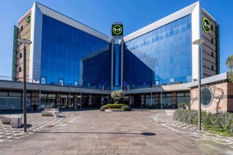 Modern building with large reflective blue glass windows and B&B Hotel Expo Verona Villafranca logos on top and sides