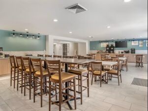 Dining area with wooden chairs and tables alongside a coffee station at Garner Hotel Panama City Beach Northeast