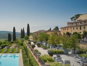 Outdoor terrace and pool area with lounge chairs and greenery at COMO Castello Del Nero Hotel & Spa under clear sky