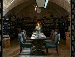 dining table with candles and flowers surrounded by cushioned chairs in the wine cellar room at COMO Castello Del Nero Hotel & Spa