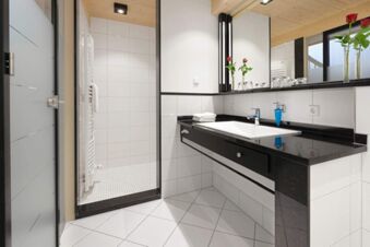 Modern hotel bathroom at Landhotel Krone with black countertop, white sink, large mirror, and walk-in shower area with white tiles