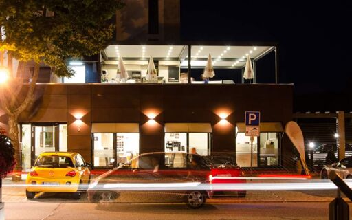 陶尔米纳酒店外墙夜景，窗户、停放的汽车和有顶的露台被照亮。