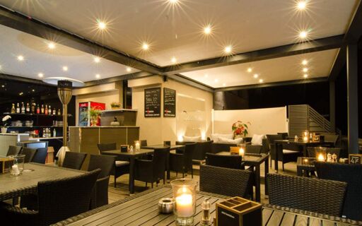 陶尔米纳酒店（Hotel Taormina）舒适而现代的灯光酒吧，内设桌子、烛光和各种饮料。