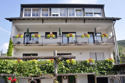White multi-story building with balconies decorated with flower pots and green plants at Hotel - Pension Wendland