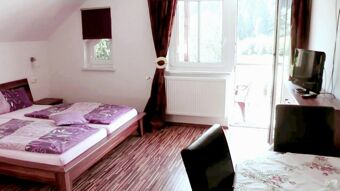 Hotel Restaurant Pension Weiherm&uuml;hle bedroom with double bed, purple bedding, window, balcony door, TV, and dark curtains
