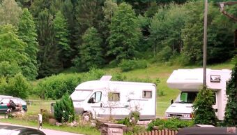 Kaks matkaautot rohelisel heinamaal tiheda metsa ees, maapiirkonnas hotell-restorani Pension Weiherm&uuml;hle l&auml;hedal.