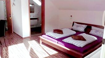 Bedroom with wooden floor and double bed with purple mattress and checkered bedding at Hotel Restaurant Pension Weiherm&uuml;hle