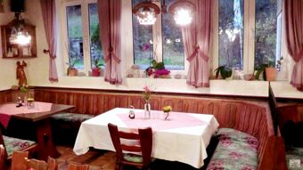 Dining area with wooden benches and floral cushions at Hotel Restaurant Pension Weiherm&uuml;hle featuring tablecloths and flower vases