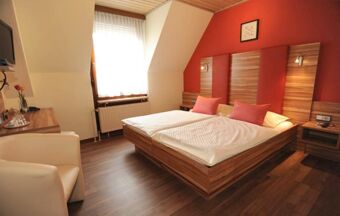 Hell eingerichtetes Hotelzimmer im Hotel R&ouml;ssle mit Doppelbett, Holzm&ouml;beln und einem Fenster mit wei&szlig;em Vorhang.