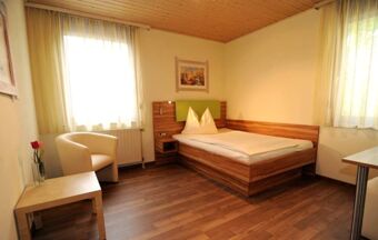 Hell eingerichtetes Einzelzimmer mit Bett, Sesseln und Fenster im Hotel R&ouml;ssle, schlicht und gem&uuml;tlich gestaltet.