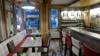 Gem&uuml;tliche Bar mit Holztheke und Sitzbereich im Hotel R&ouml;ssle, dekoriert mit Weinflaschen und warmem Licht, einladend und stilvoll.