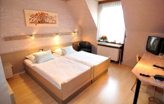 Modern eingerichtetes Doppelzimmer im Hotel R&ouml;ssle mit zwei Einzelbetten, Schreibtisch, TV und einem Fenster mit Tageslicht.