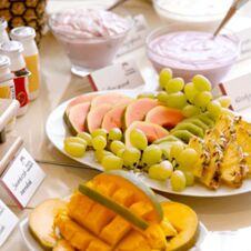 Plate of sliced melon, pineapple, kiwi, and green grapes with bowls of yogurt on a breakfast table at Hotel Hahnen