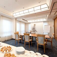 Moderne konferanserom i Hotel Hahnen med et stort bord, komfortable stoler og naturlig lys gjennom store vinduer.