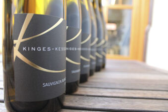 Rows of Sauvignon Blanc wine bottles with black and gold labels from Winzerhotel Weingut Kinges-Kessel on a wooden surface