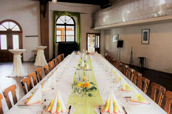 Long dining table set with glassware, sunflower napkins, candles, and greenery in a room at Winzerhotel Weingut Kinges-Kessel