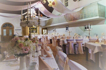 Banquet hall at Winzerhotel Weingut Kinges-Kessel with tables set with white cloths, pink napkins, and floral centerpieces