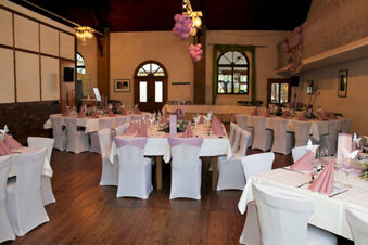 Banquet room with white covered chairs, tables set with pink napkins and butterfly decorations at Winzerhotel Weingut Kinges-Kessel