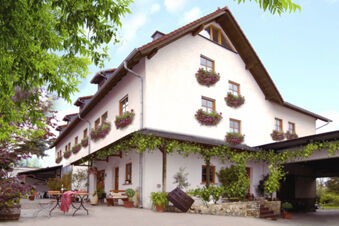 White three-story building with flower boxes under windows and outdoor seating at Winzerhotel Weingut Kinges-Kessel