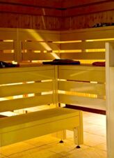 Wood-paneled sauna room with wooden benches and folded towels at Landgasthof Hirsch Dapfen