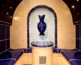 Interior of a tiled room at Landgasthof Hirsch Dapfen featuring beige and dark blue tiles with a large blue vase mounted on the wall