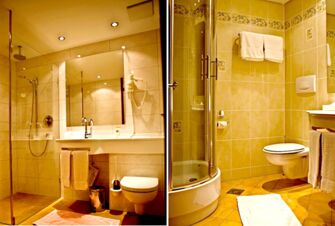 Bathroom with shower, sink, toilet, towels, and hairdryer in Landgasthof Hirsch Dapfen with yellow tiles and lighting