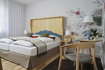 Modern eingerichtetes Doppelzimmer mit hellem Holzm&ouml;bel und floraler Tapete im Hotel Restaurant Klosterhof GmbH.