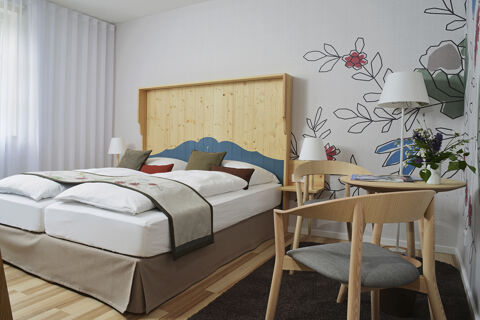 Modern eingerichtetes Doppelzimmer mit hellem Holzm&ouml;bel und floraler Tapete im Hotel Restaurant Klosterhof GmbH.