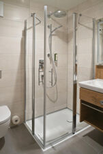 Moderne Badezimmerdusche mit Glasabtrennung und wei&szlig;en Fliesen im Hotel Restaurant Klosterhof GmbH, erg&auml;nzt durch Waschbecken und Toilette.