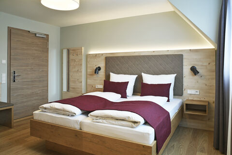 Modernes Doppelzimmer mit Holzm&ouml;beln, wei&szlig;en Bettw&auml;sche und roten Akzenten im Hotel Restaurant Klosterhof GmbH. Einladendes Ambiente.