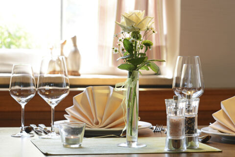 Fein gedeckter Tisch mit Weingl&auml;sern, Servietten und einer wei&szlig;en Rose als Dekoration im Hotel Restaurant Klosterhof GmbH.
