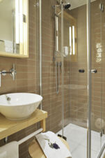 Modernes Badezimmer mit Glasdusche, Waschbecken und Holzm&ouml;beln im Hotel Restaurant Klosterhof GmbH elegant gestaltet.