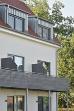 Fassade des Hotels mit modernen Balkonen und Dachfenstern, umgeben von B&auml;umen, Hotel Restaurant Klosterhof GmbH in nat&uuml;rlicher Umgebung.