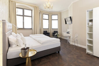 Hotel room at Lodner&acute;s Genie&szlig;erhotel & Hotel Drei Mohren with a double bed, side table with champagne, chandelier, and two chairs by the window